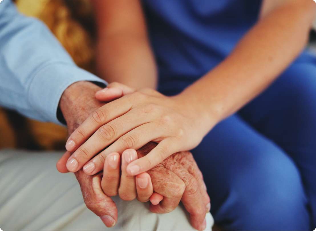 A caregiver holding a resident’s hand